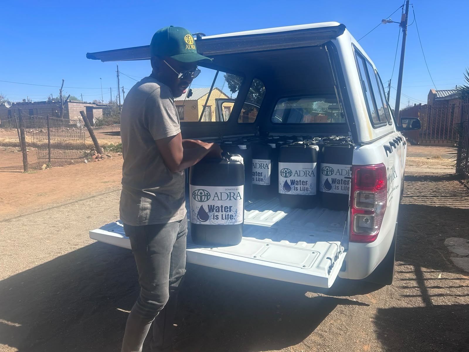 ADRA team member unloading Water is Life containers from a pickup truck