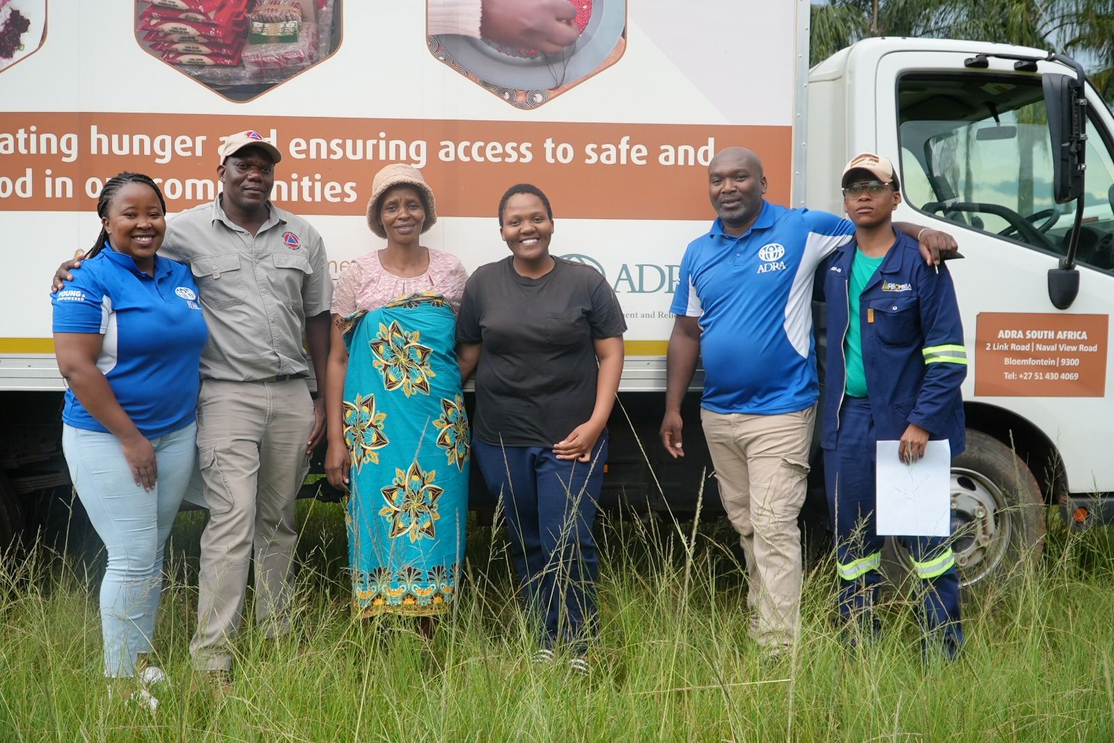 ADRA South Africa staff and community partners standing beside a food-security delivery truck